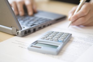 Cropped image of woman's hands calculating home finances at desk